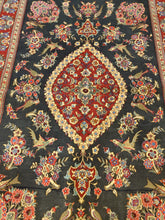 Load image into Gallery viewer, Close up of the red medallion  bordered by rosette in a black floral field of a Qom Rug