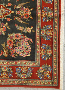 close up view of a Qom Handknotted rug's  bottom left corner floral border